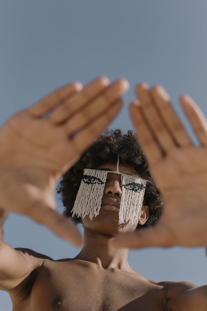 about-us-02 Artistic portrait of a man with an eye mask making a pyramid hand gesture in a low angle shot.